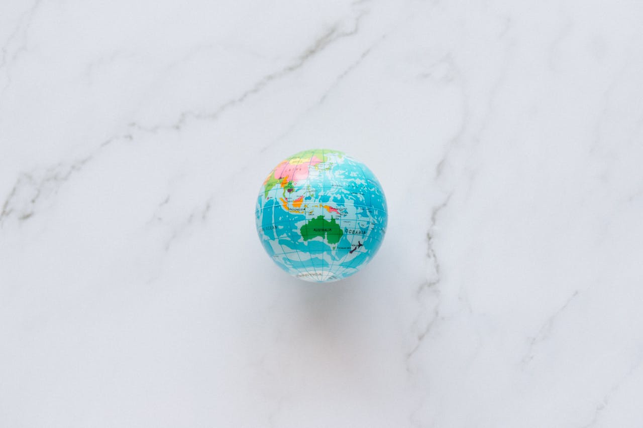 A small, colorful globe rests on a marble surface, symbolizing global exploration and travel planning.